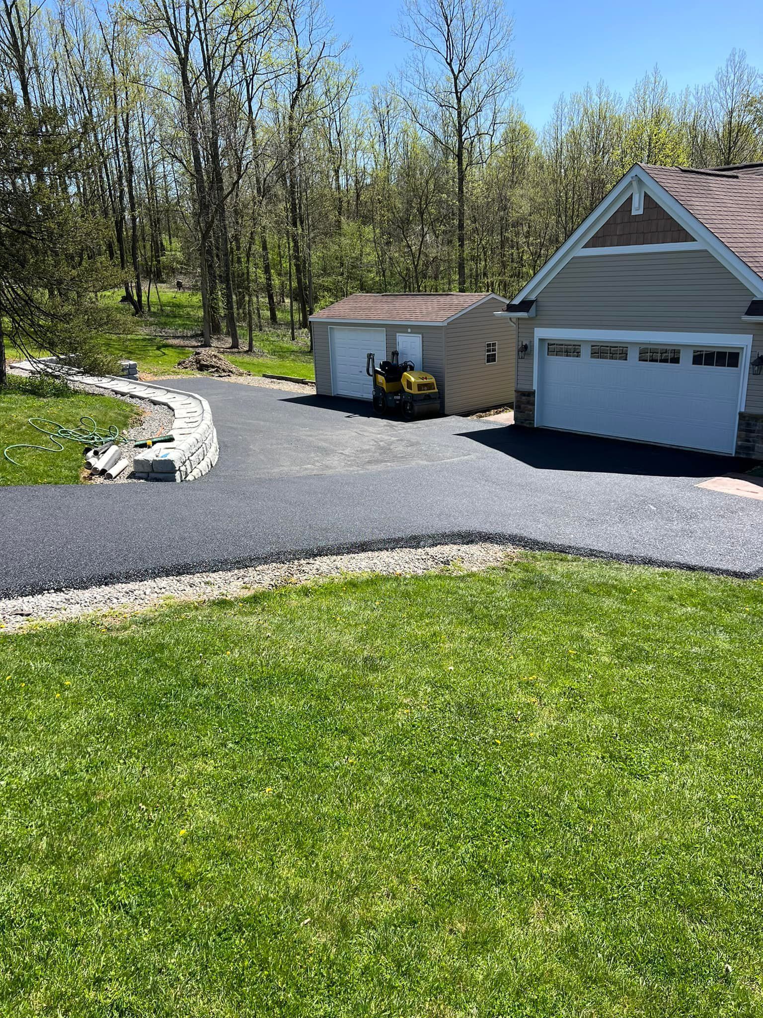 A driveway leading to a house with a garage and a shed.