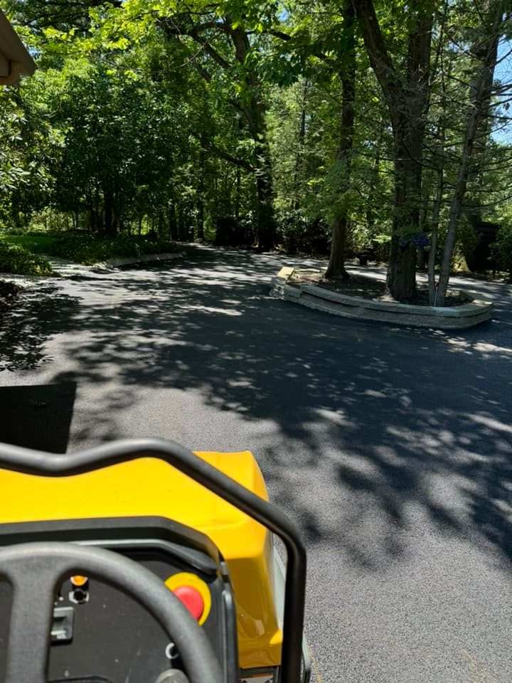 A yellow tractor is driving down a road with trees in the background.