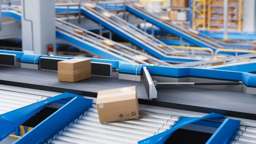 Blue conveyor belts moving cardboard boxes in a warehouse sorting facility