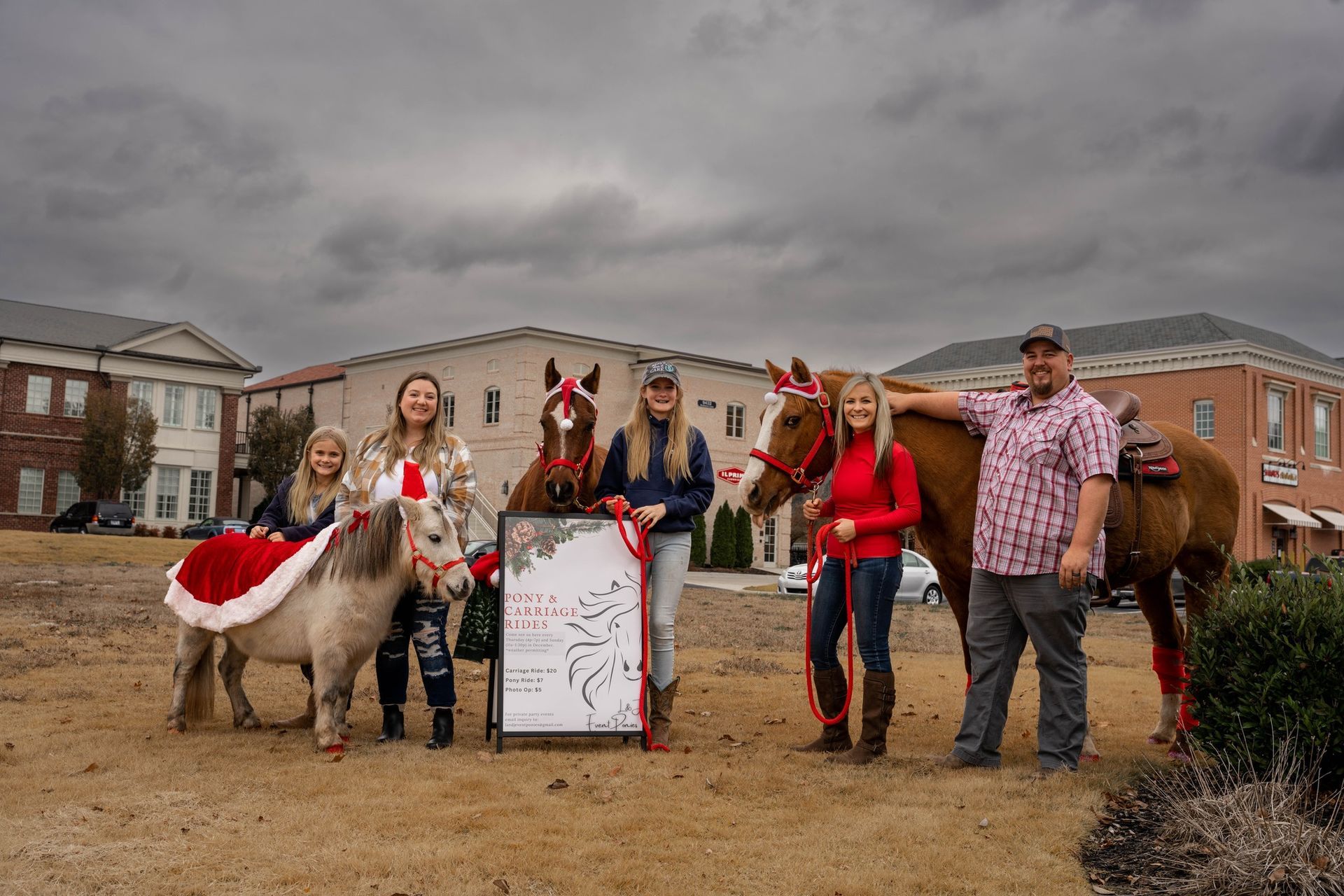A group of people standing next to horses in a field.
