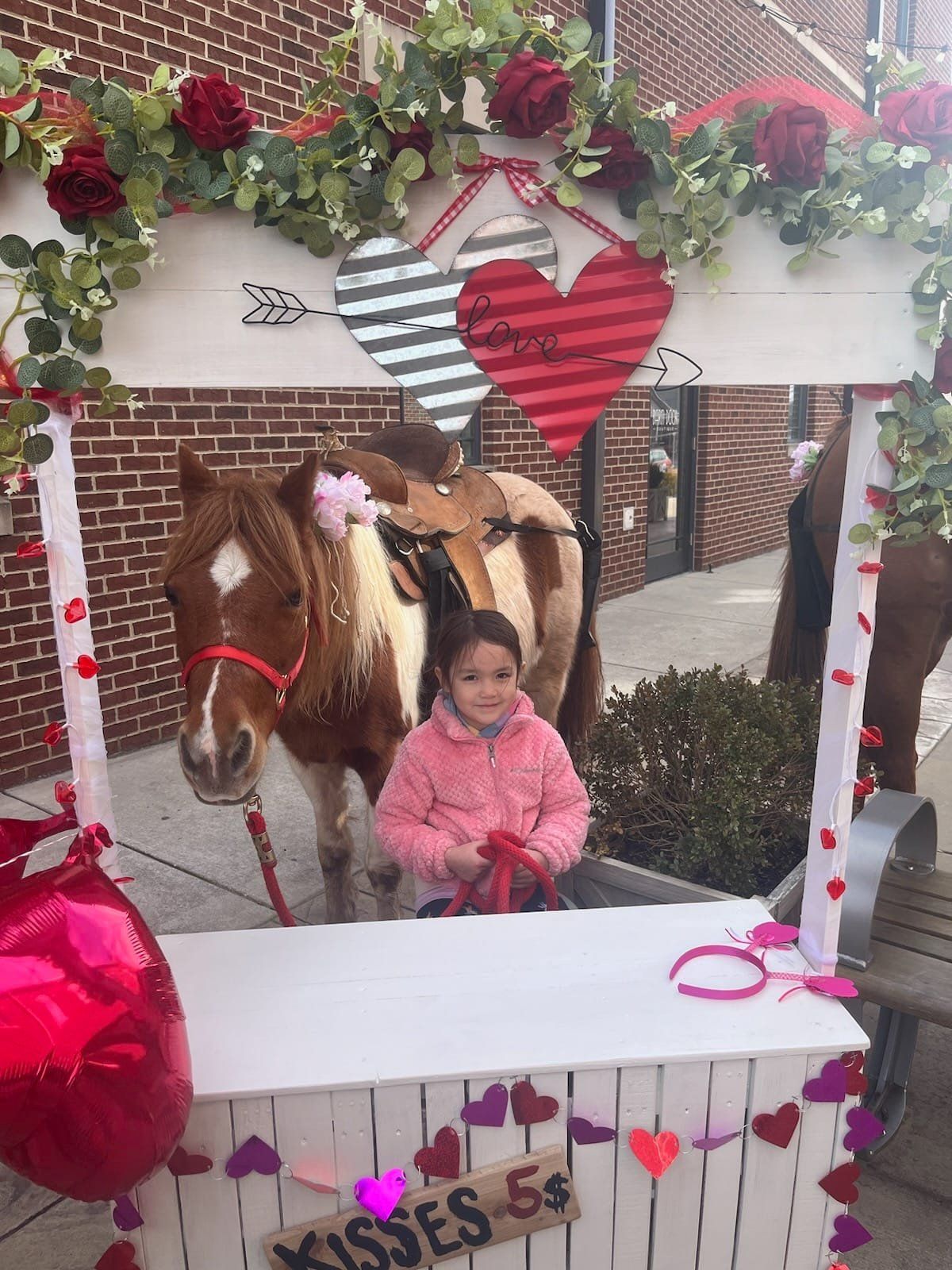 A little girl is posing for a picture with a horse.
