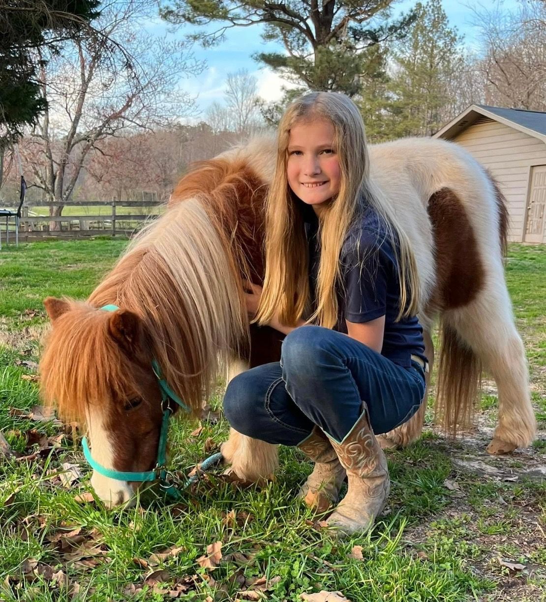 girl kneeling beside a pony 