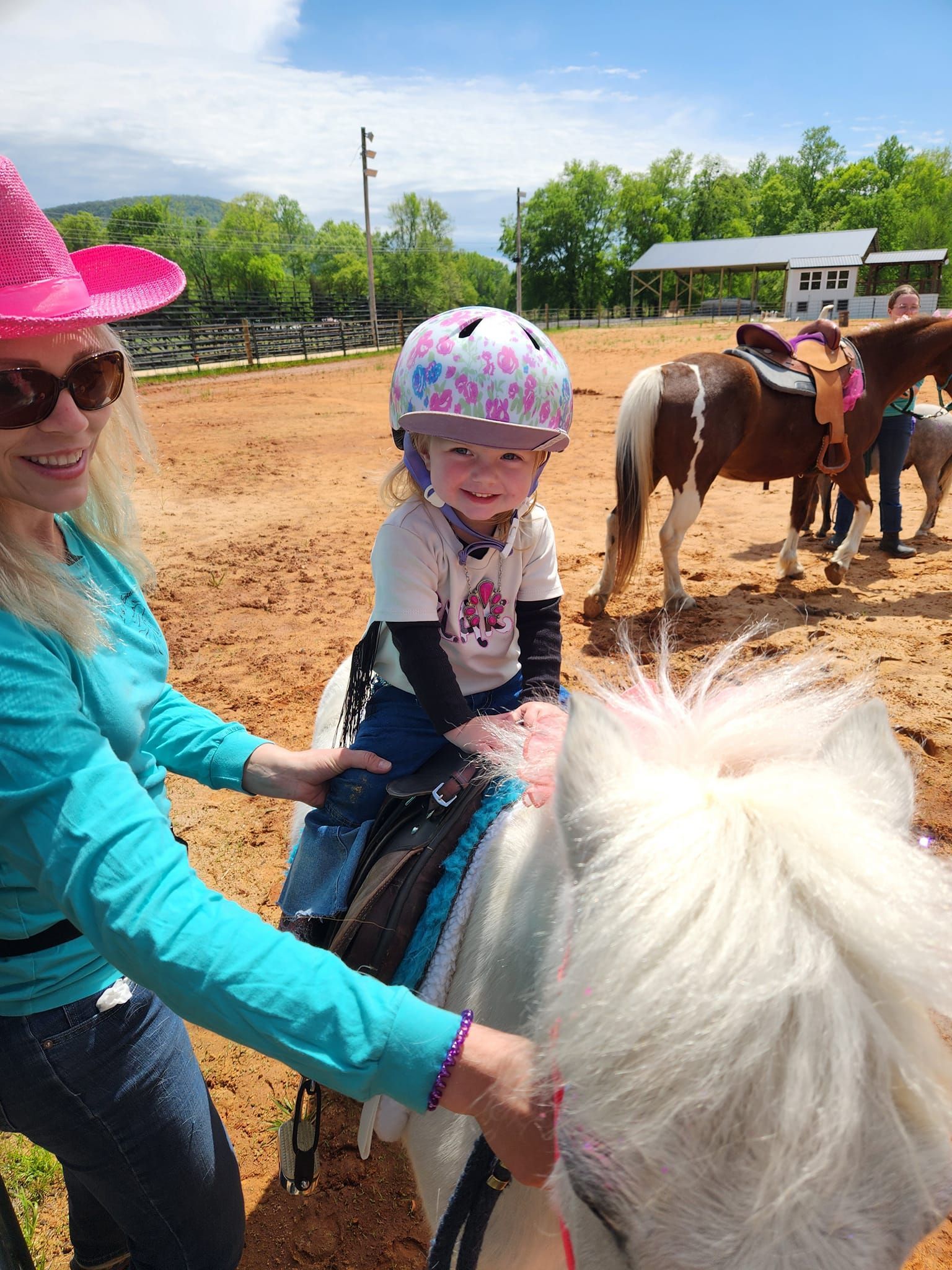 A woman is teaching a little girl how to ride a pony.