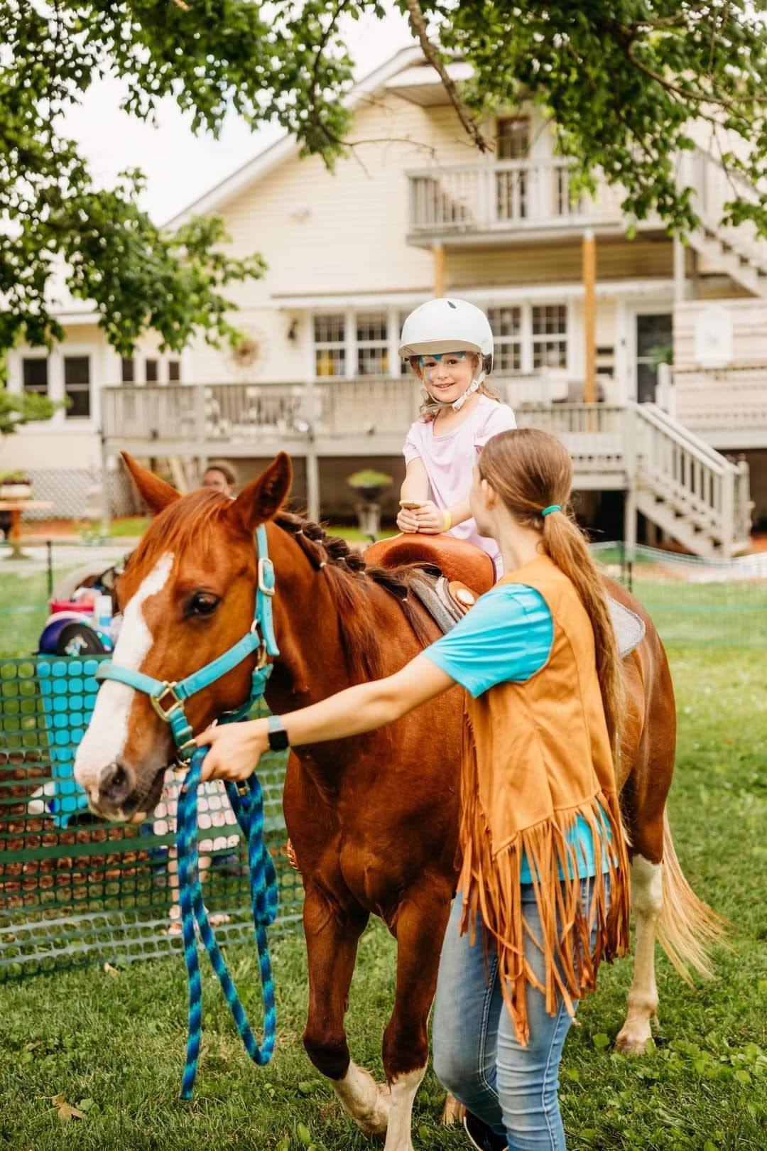 A woman is helping a little girl ride a horse.