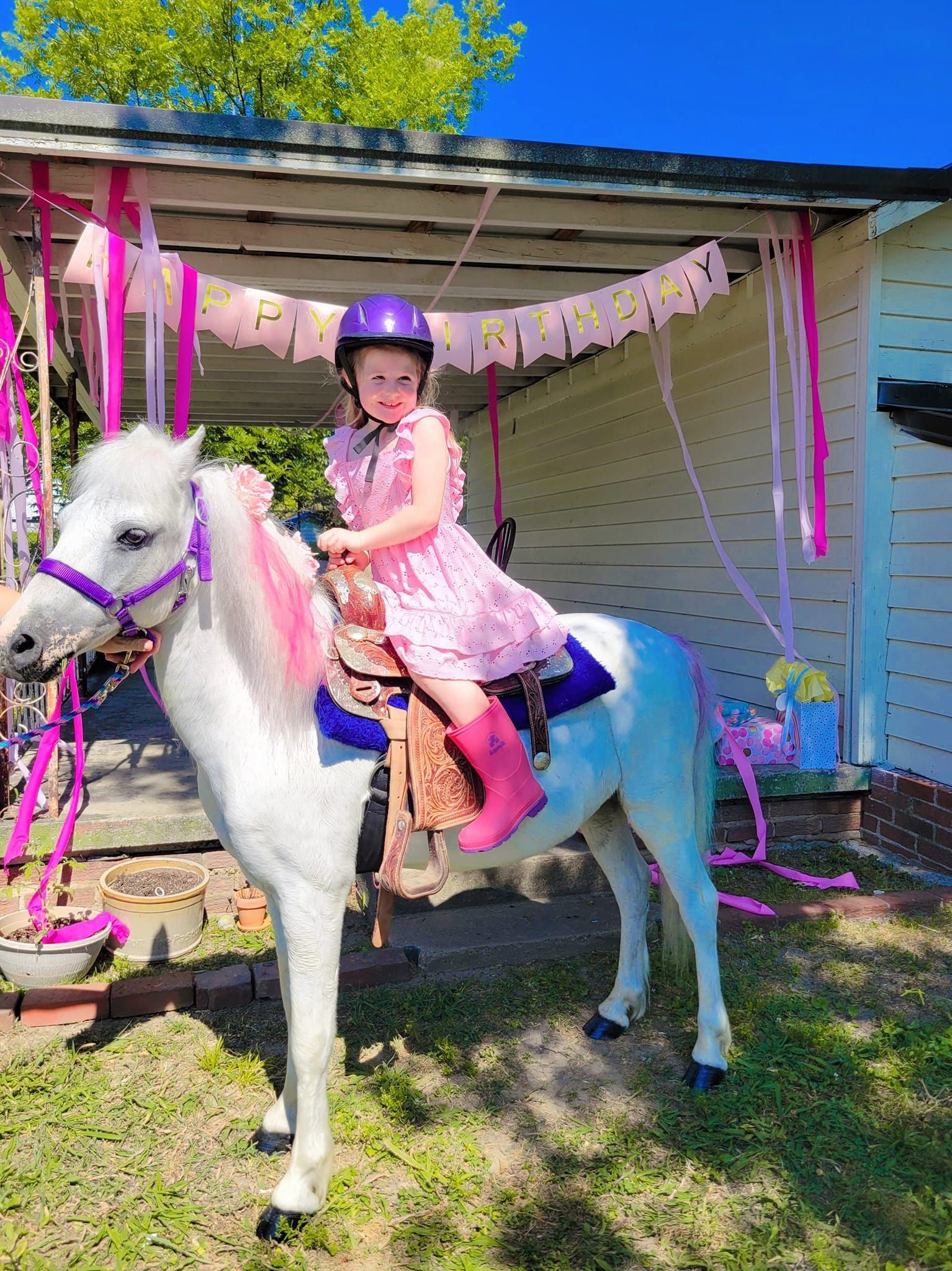 A little girl is riding on the back of a white pony.