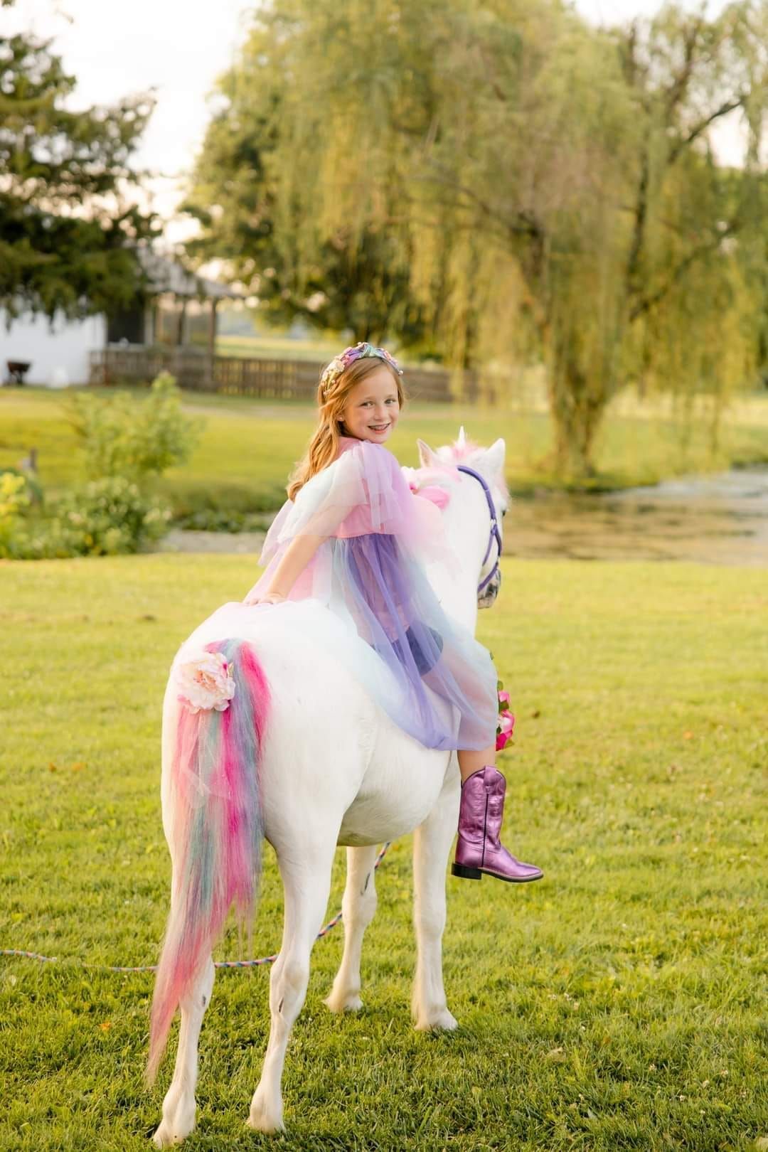 A little girl is riding on the back of a white horse.