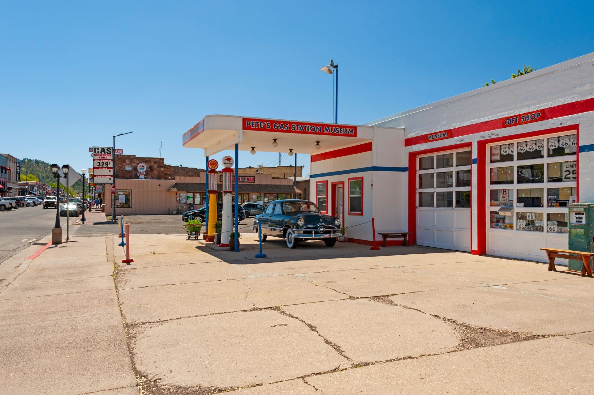 Classic gas station with red and white trim, vintage car, sunny day.