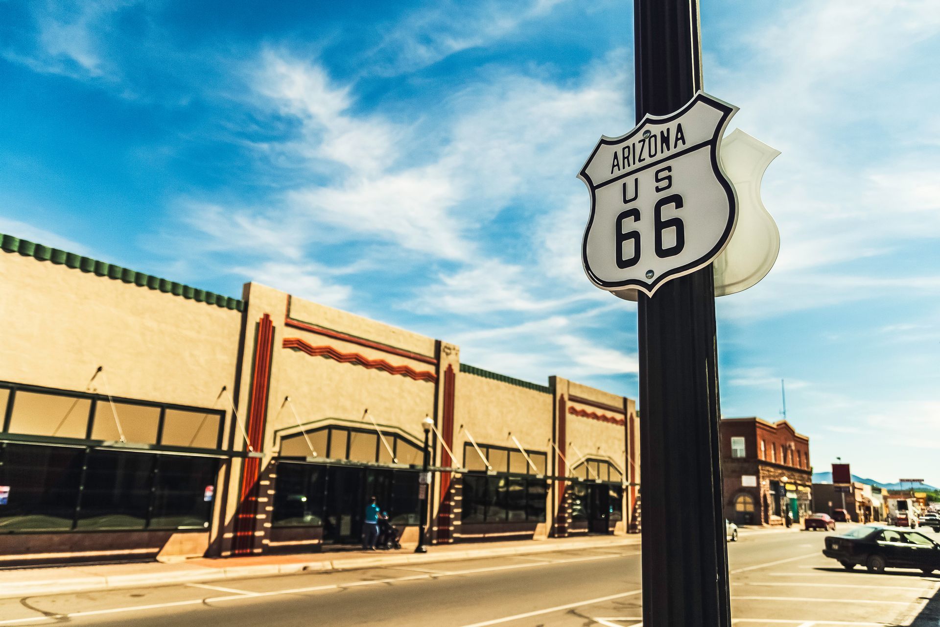 US Route 66 sign in Arizona, with vintage storefronts along the street under a blue sky.
