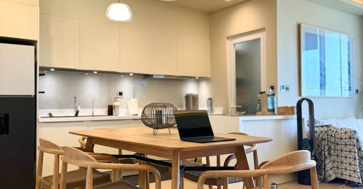 A kitchen with a table and chairs and a laptop on it.