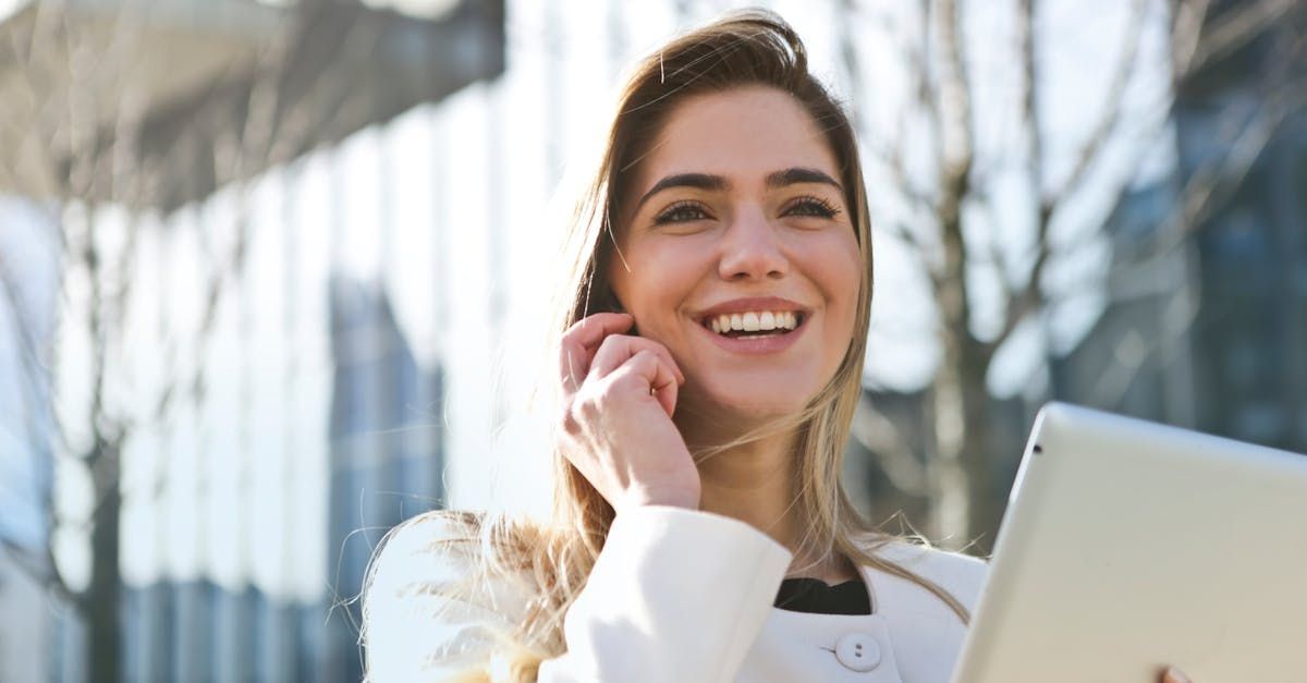 A woman is talking on a cell phone while holding a tablet.