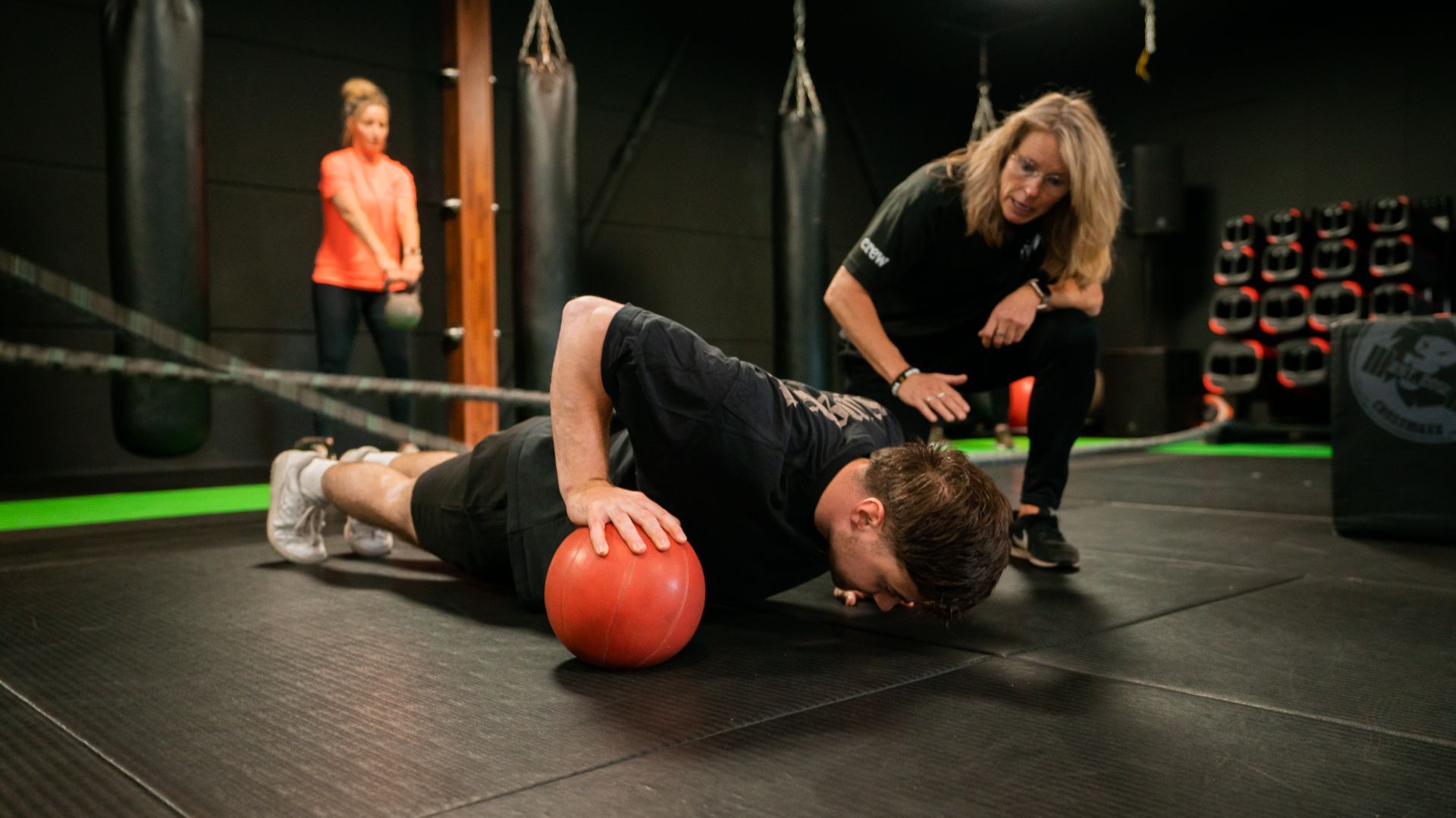 Een vrouw helpt een man met push-ups met een bal in een sportschool.