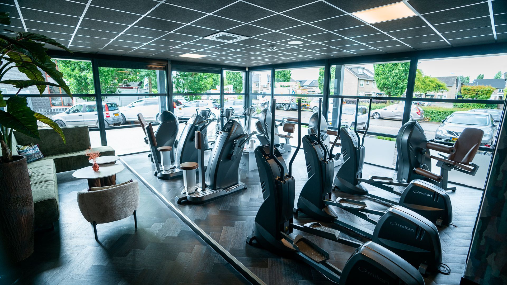 Een sportschool met veel fitnessapparatuur en veel ramen.