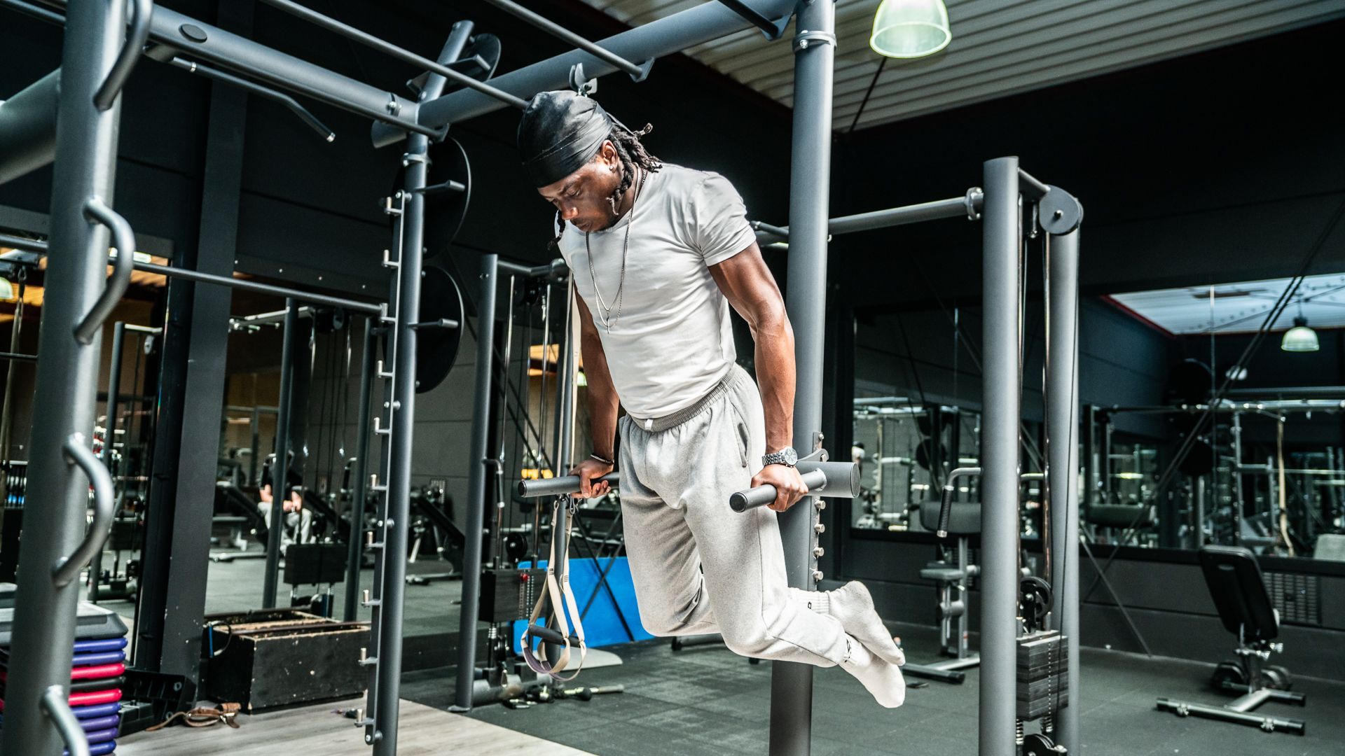 Een man doet dips op een stang in een sportschool.