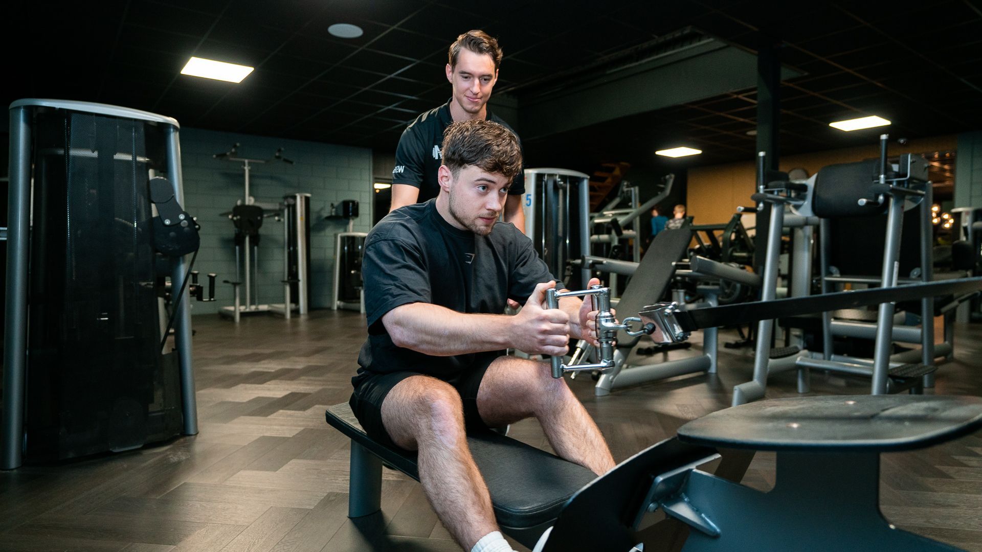 Een man tilt halters op een bankje in een sportschool.