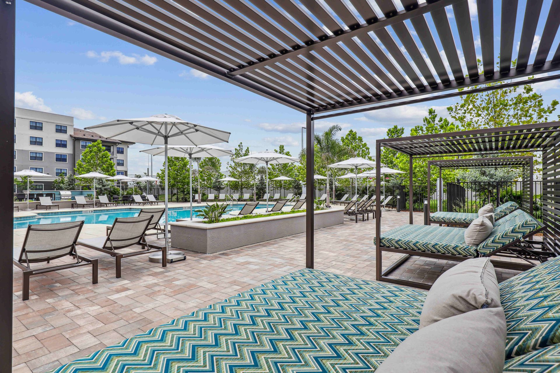 Poolside lounge area with canopy beds, umbrellas, and a swimming pool.