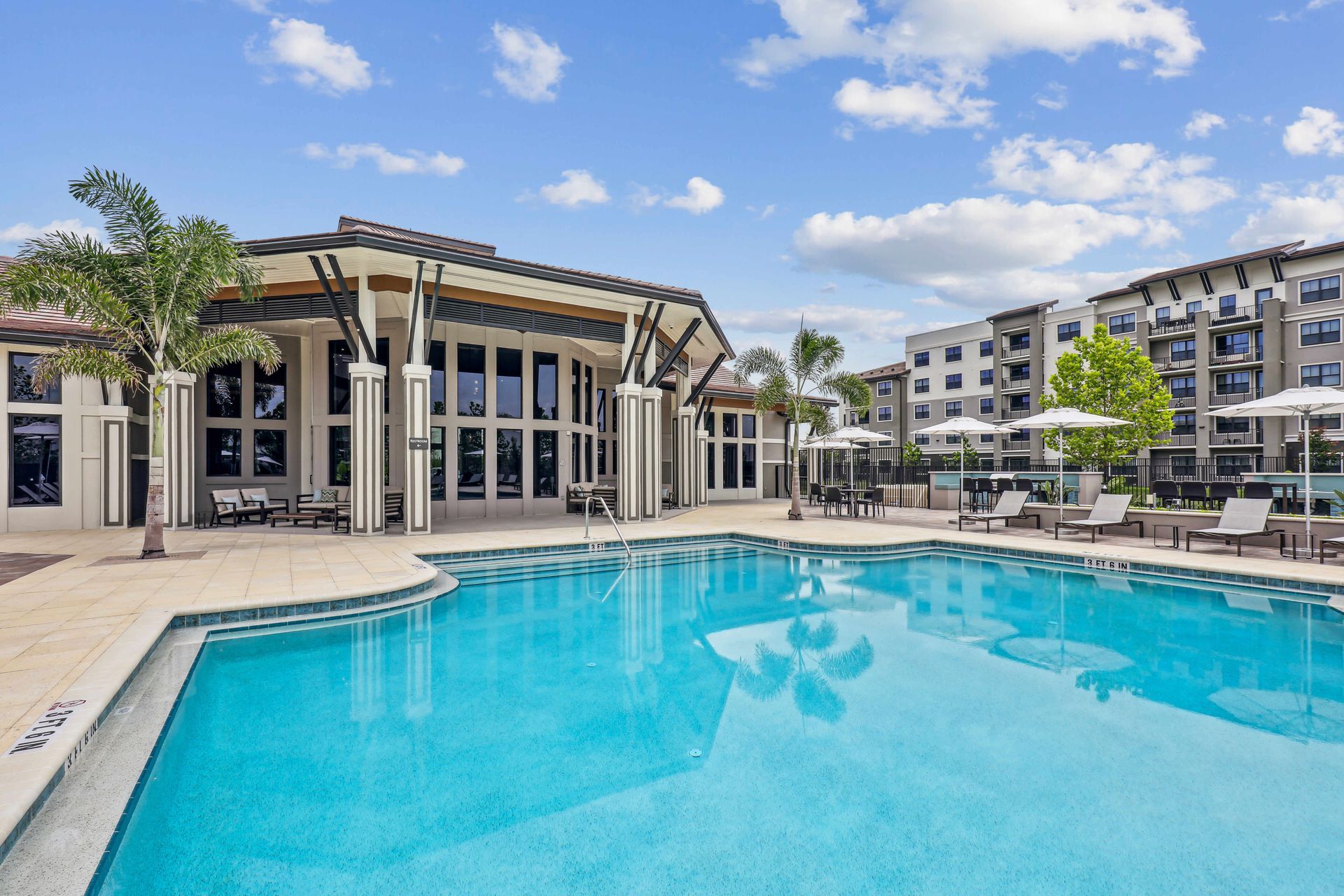 Pool with blue water and buildings in the background under a blue sky.