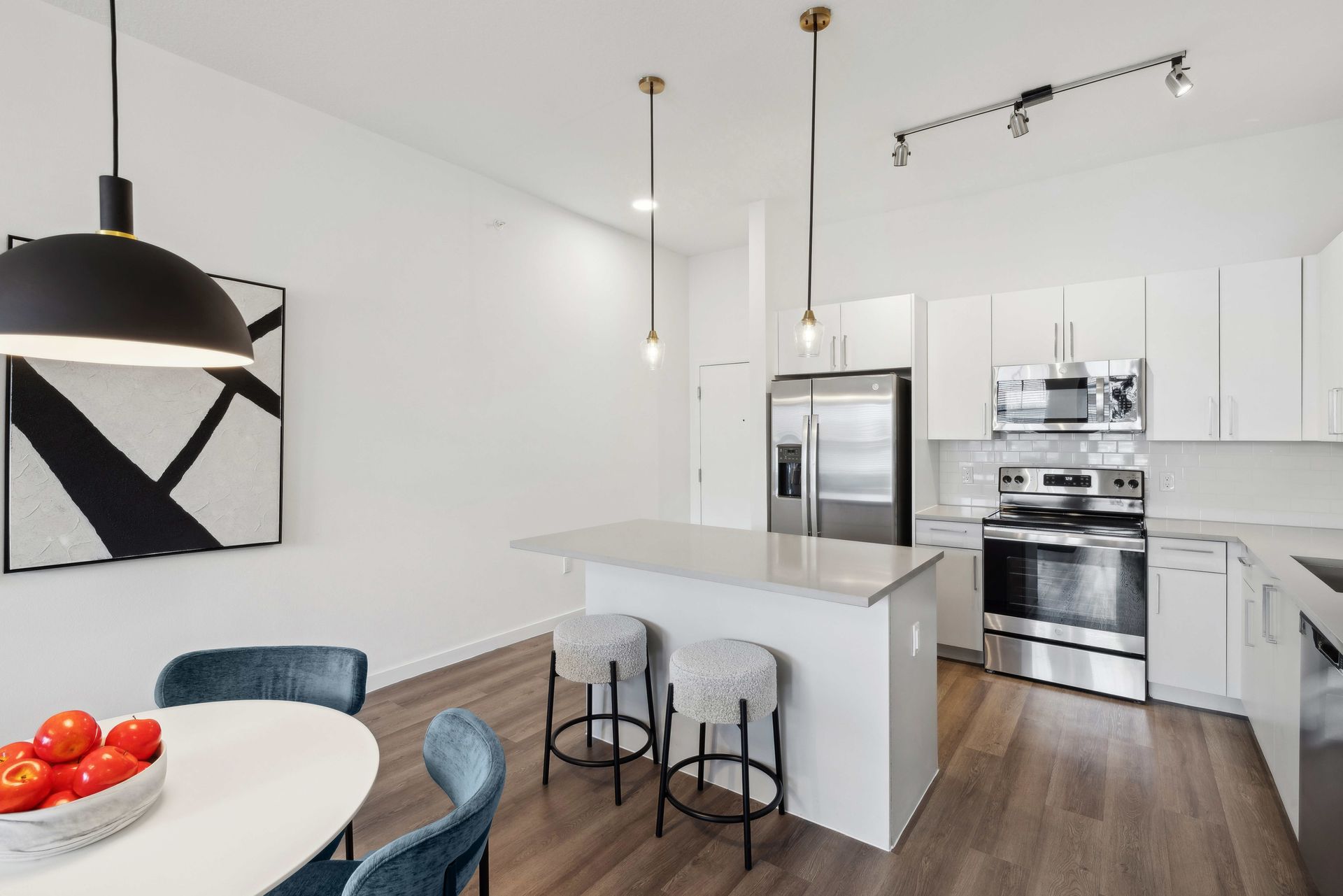 Modern kitchen with white cabinets, stainless steel appliances, and a gray island with stools.
