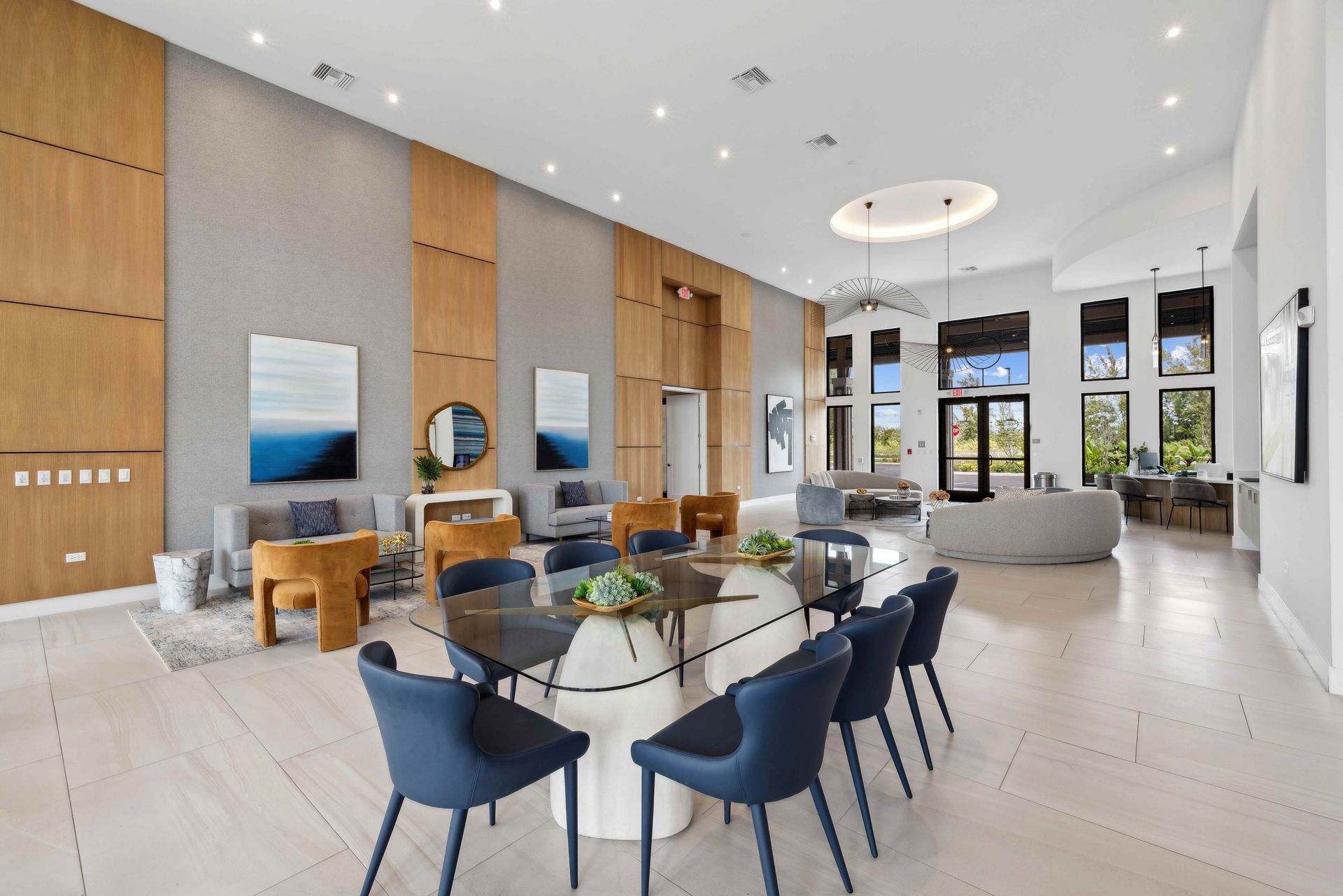 Spacious modern room with large table and blue chairs, lounge area, and wood paneling on the walls.