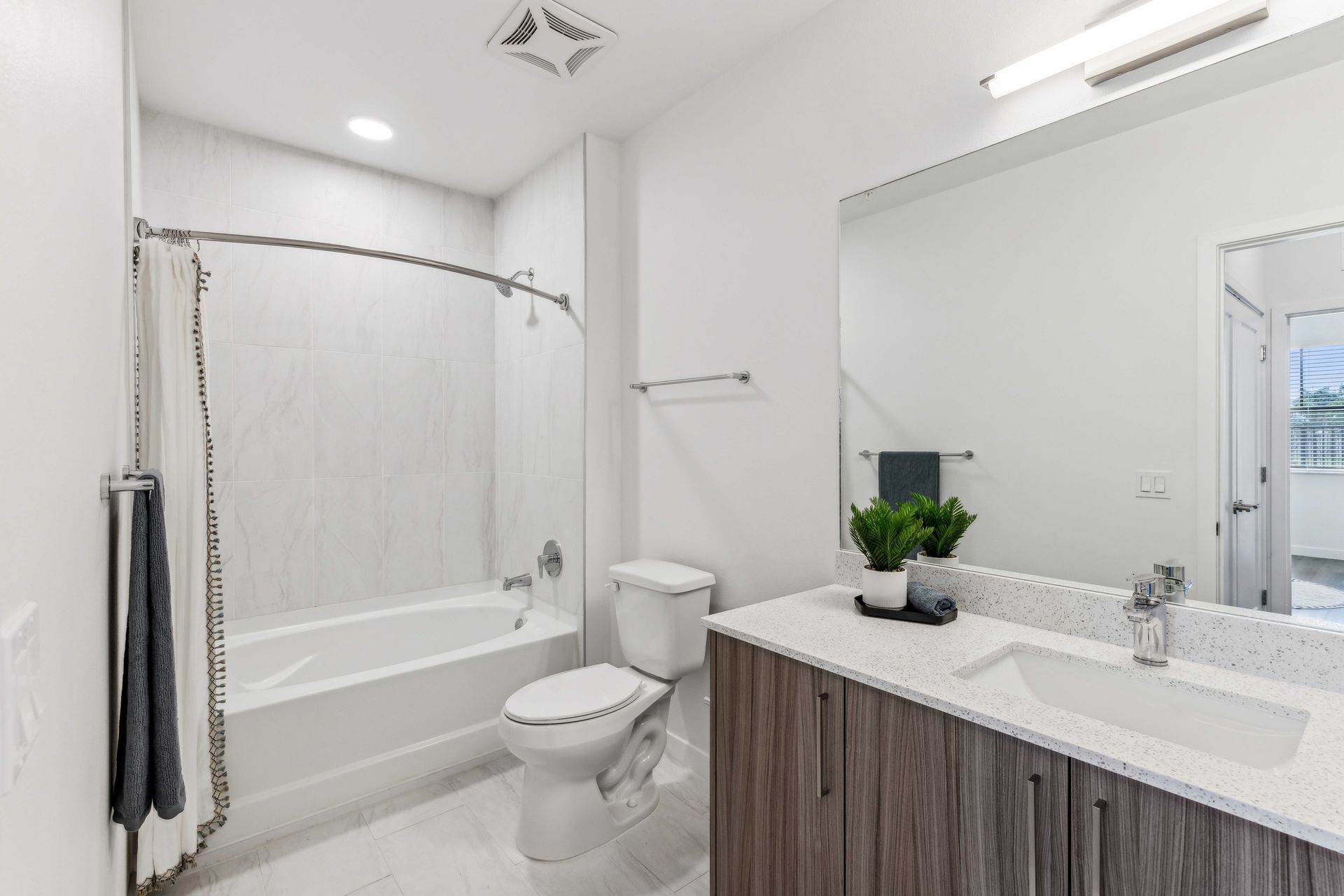 Modern bathroom with white and gray tile, vanity, toilet, and shower/tub.