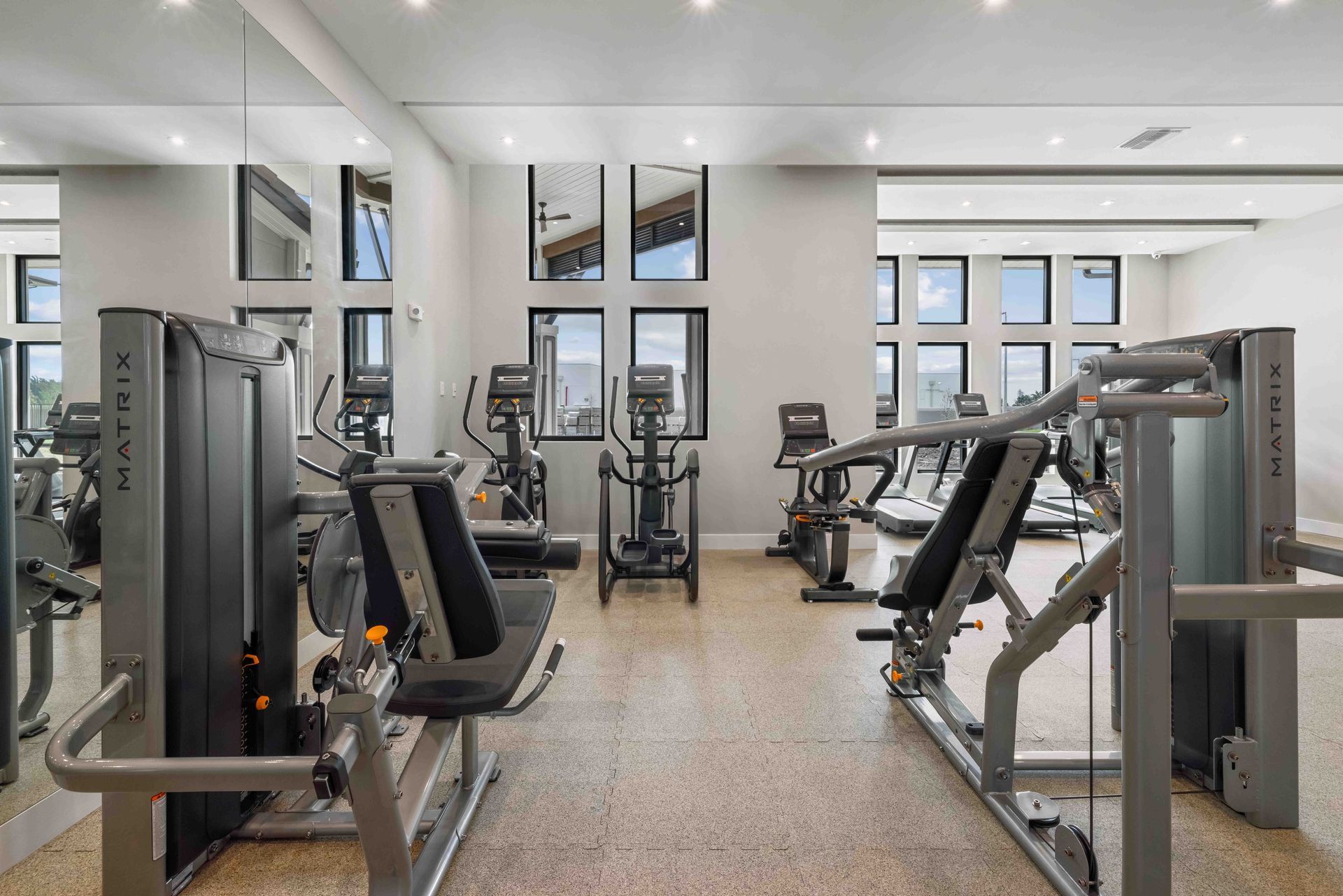 Gym with exercise machines and reflective mirrors.