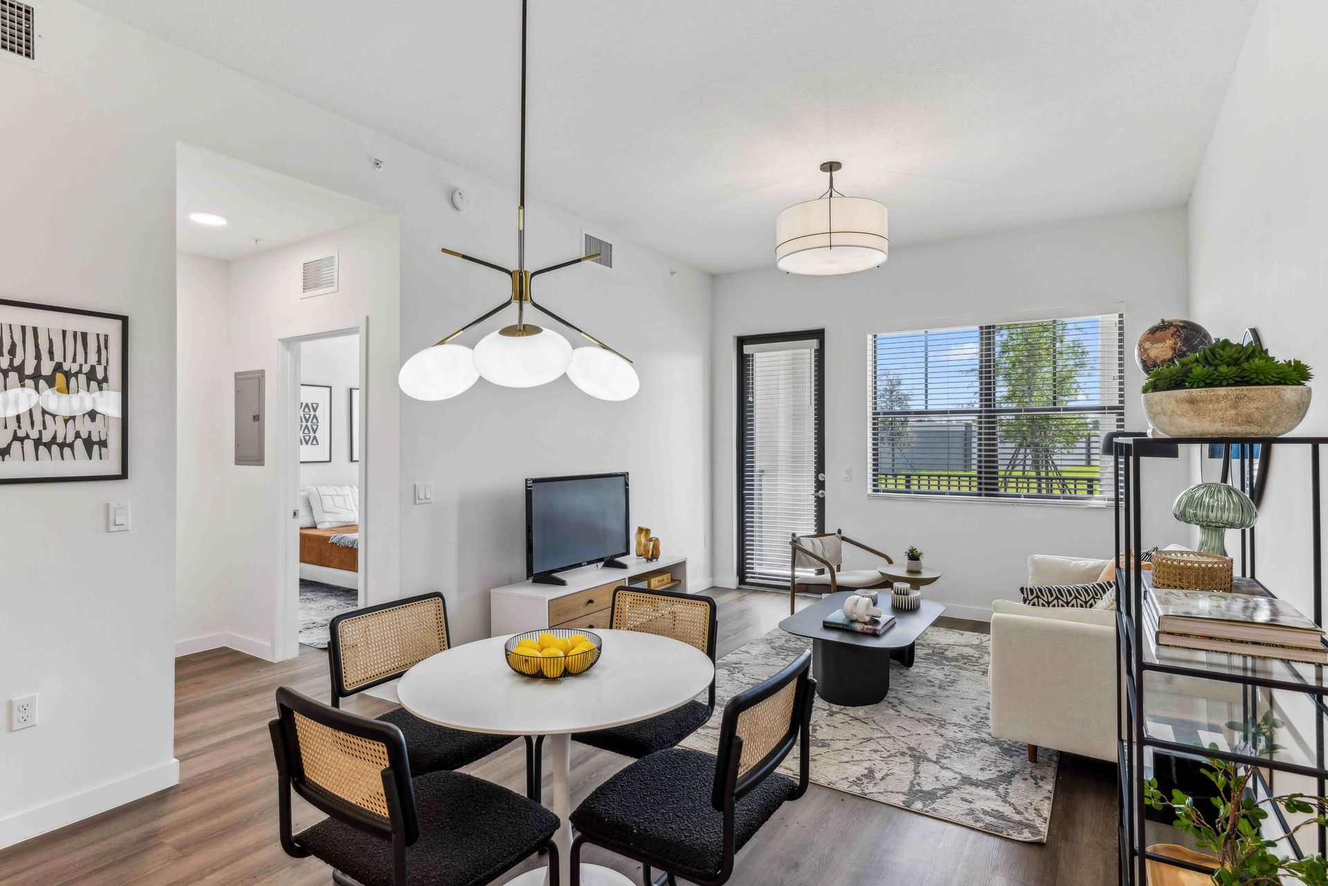 Modern living room with dining area, white walls, and view of the outdoors.