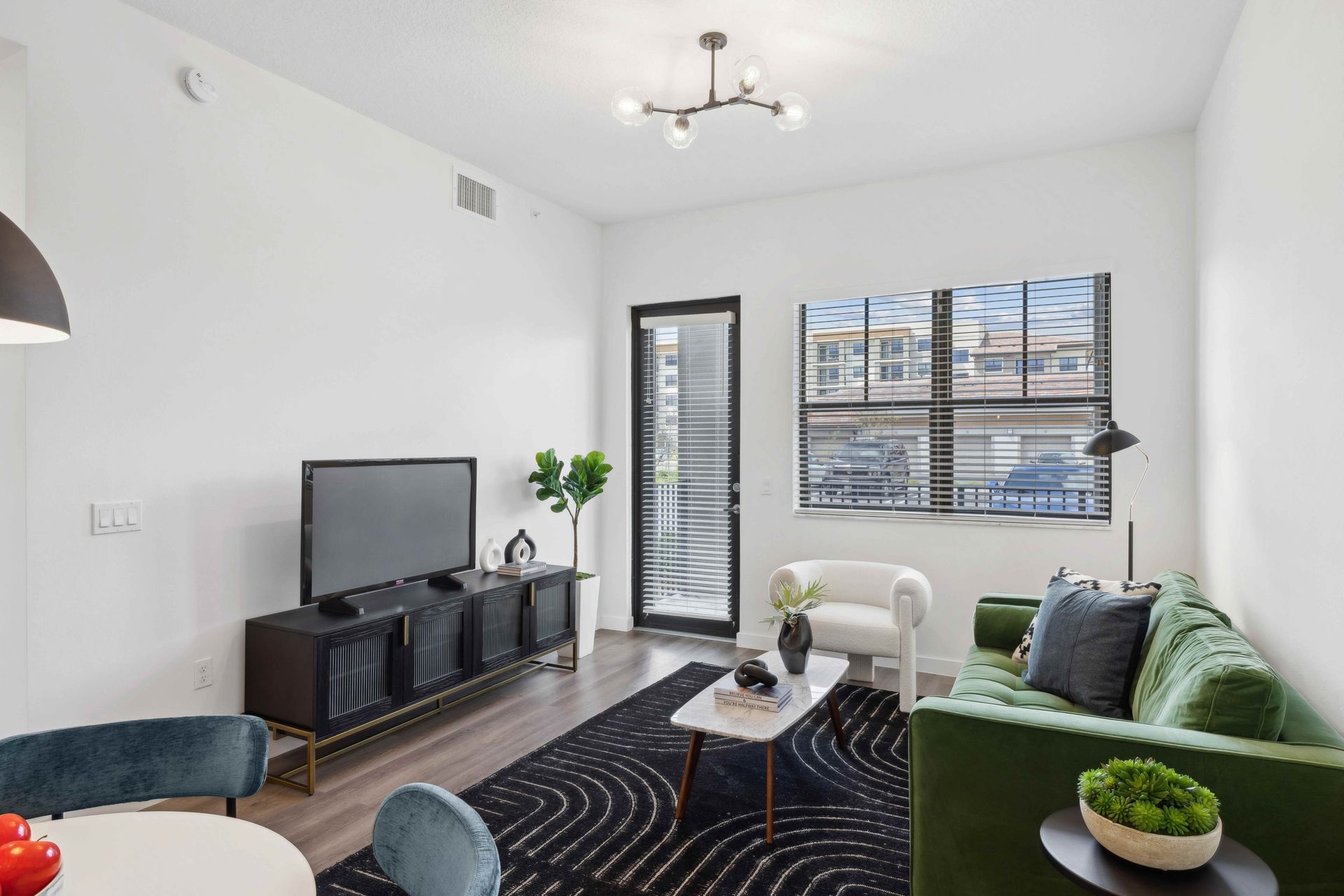 Modern living room with green sofa, black console, and large window.