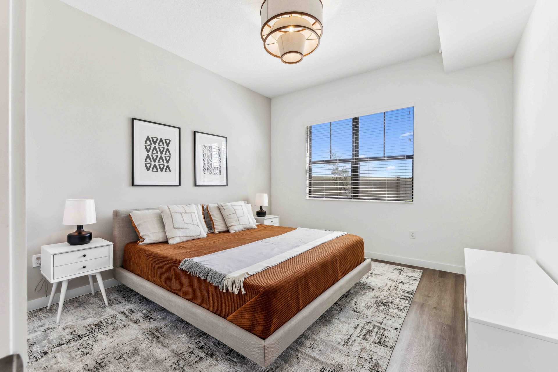 Bedroom with a bed, two nightstands, two framed prints, and a window.