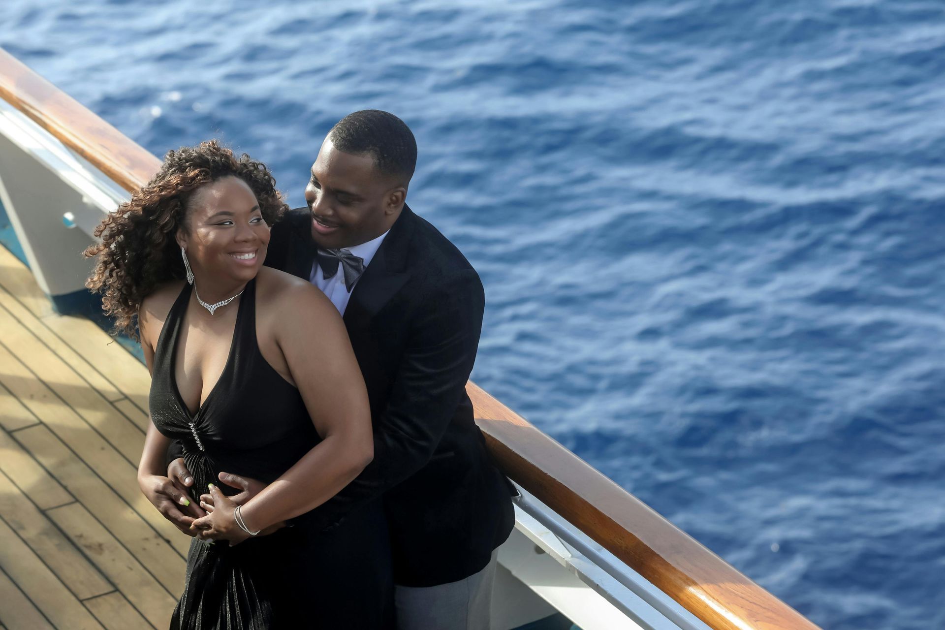 Couple embracing on cruise ship deck at sunset, romantic cruise vacation planning