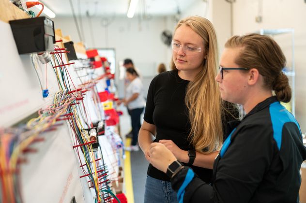 Two female Kato Cable technicians inspecting a wiring board.