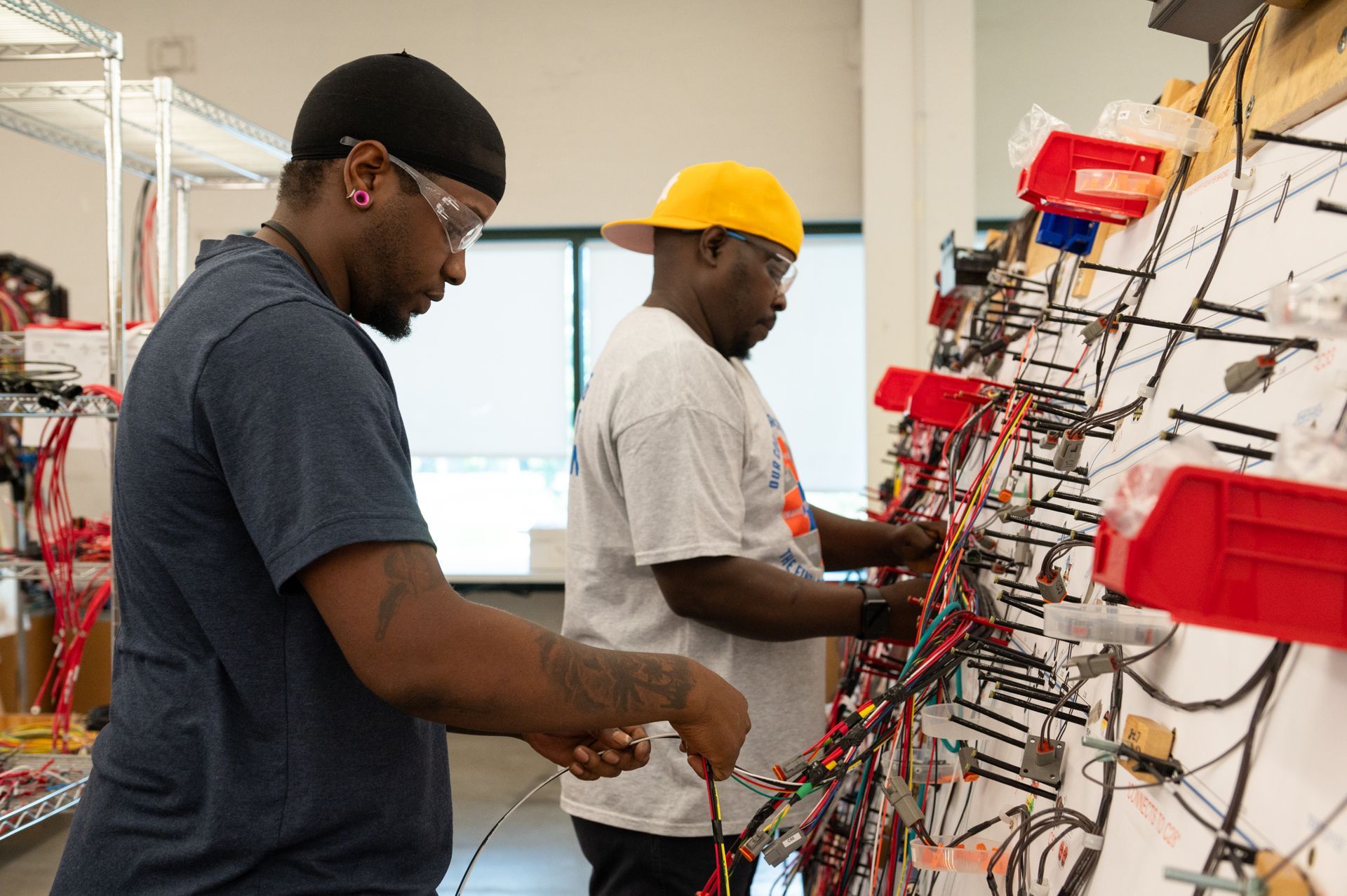Two male Kato Cable technicians working on a wiring machine.