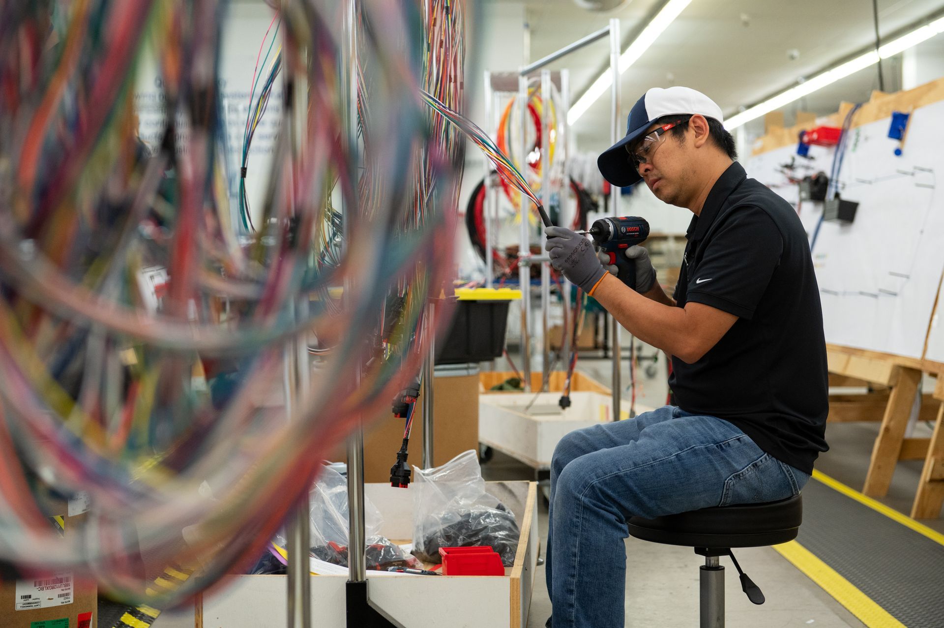 A male Kato Cable technicians inspecting wires, sitting.