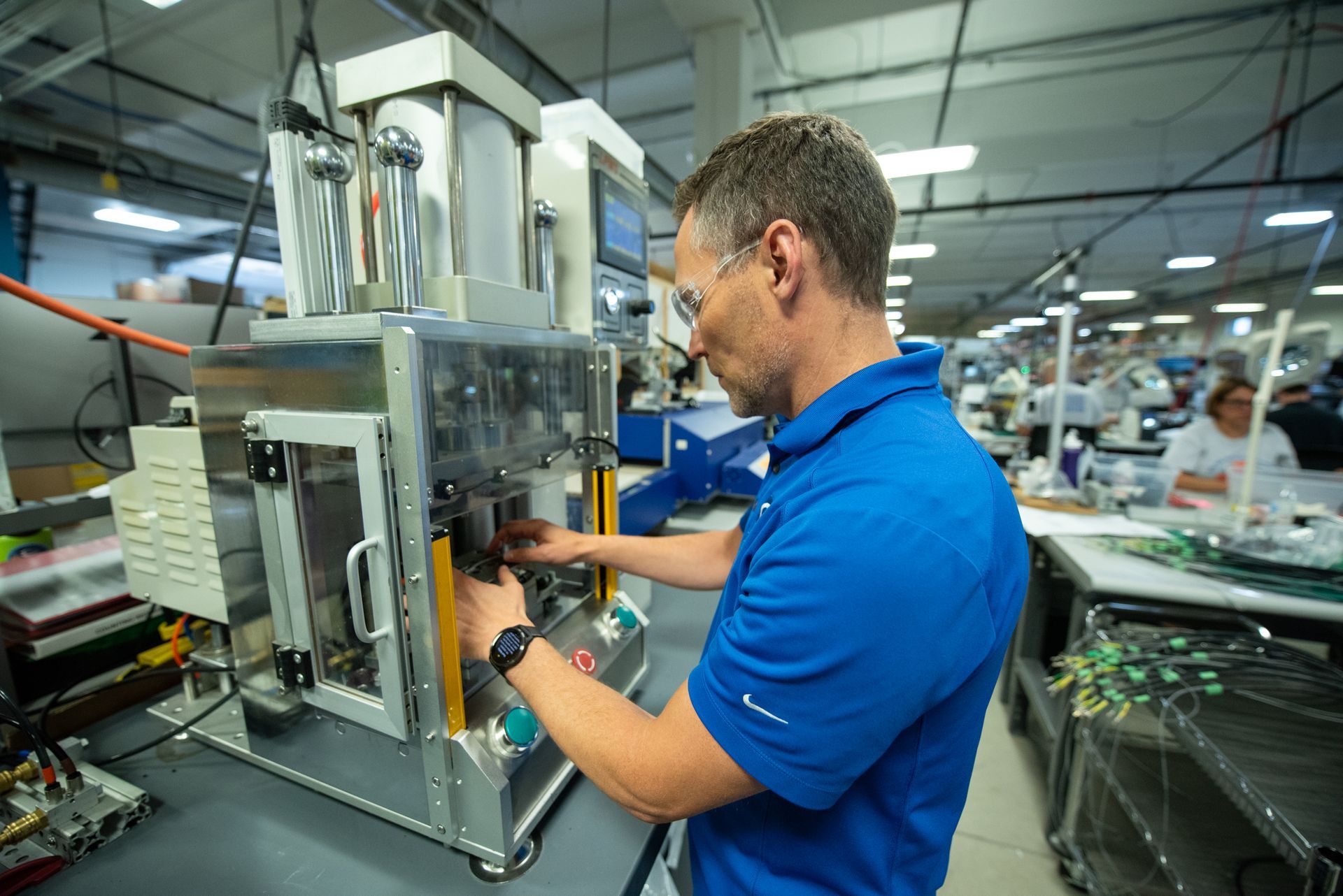 A male Kato Cable technician working on a wiring machine.
