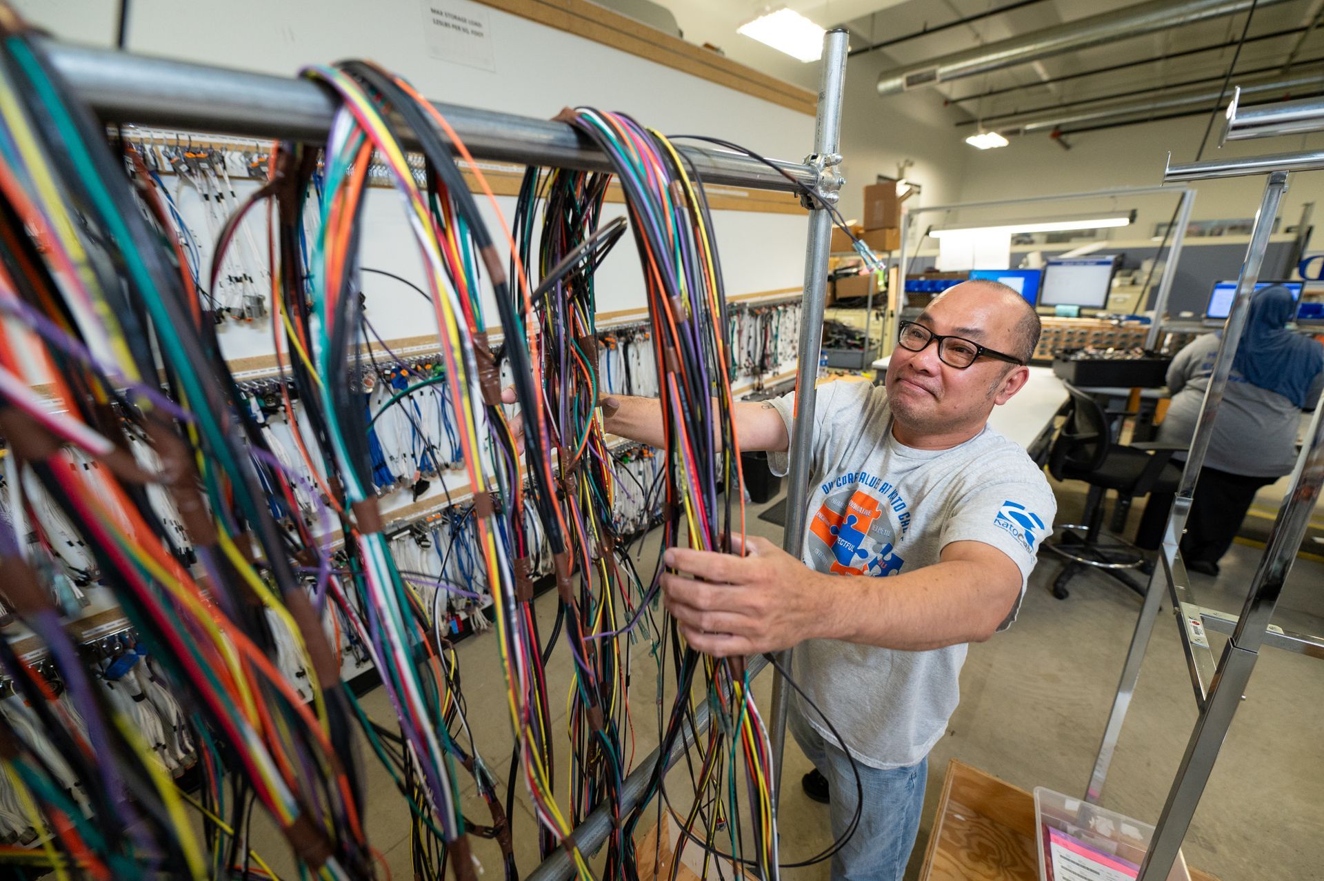 A male Kato Cable technician next to various cable assemblies.