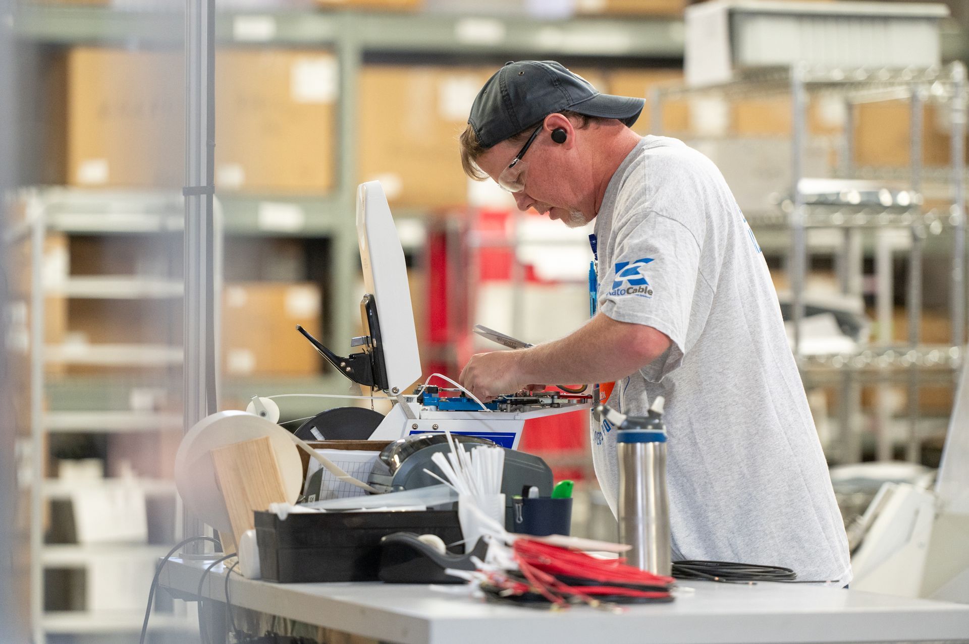 A male Kato Cable technician working on a wiring machine.