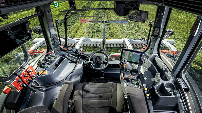 The interior of a tractor is shown with a field in the background.