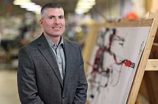 Kato Cable President Matt Lade standing beside wiring schematic in production facility