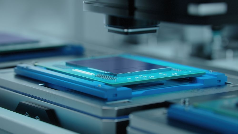 A computer chip under a machine vision camera on a factory line, blue and silver details.