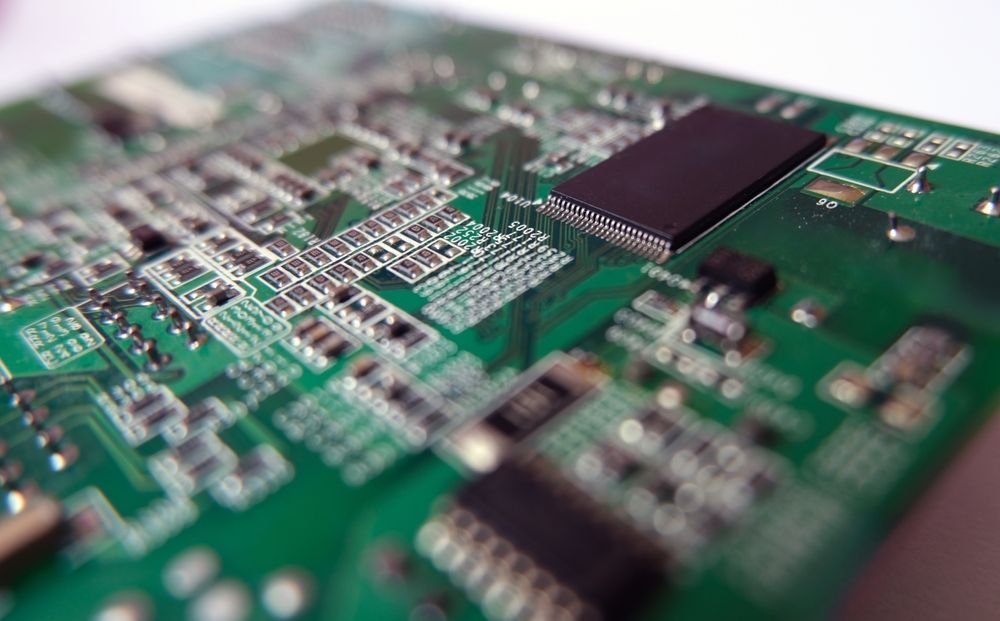Green circuit board with various electronic components.