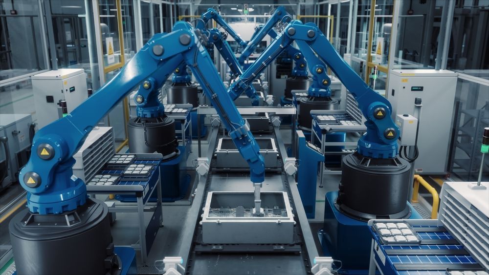 Blue robotic arms assembling products on an automated factory production line.
