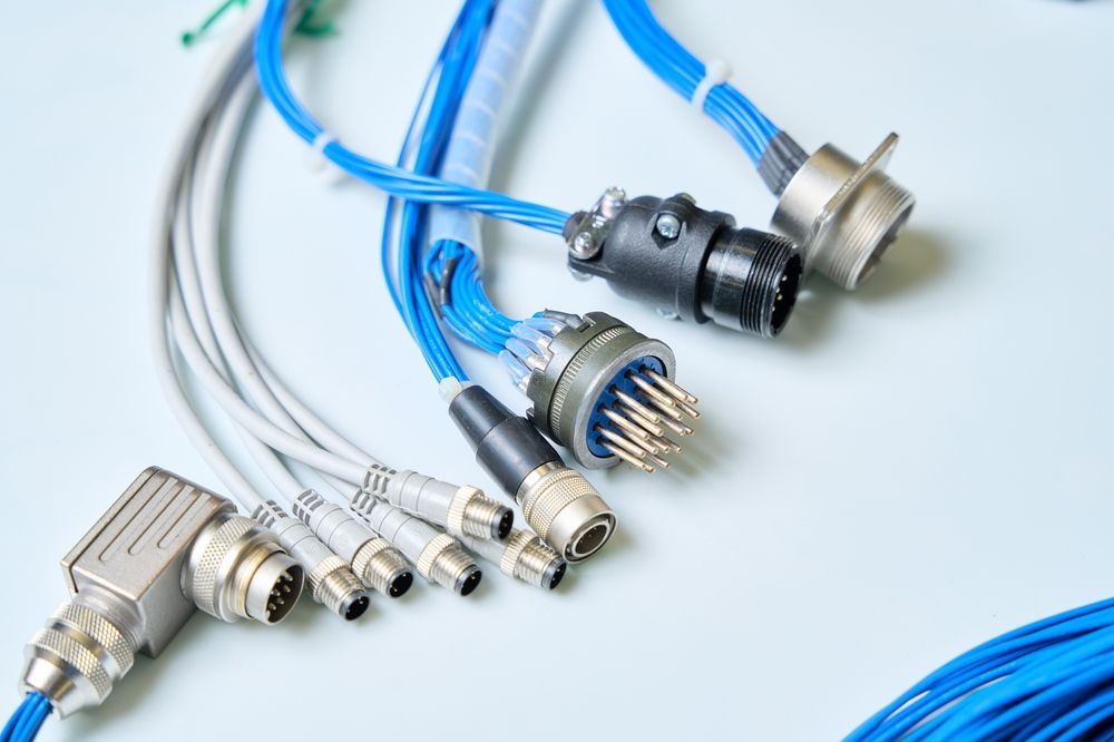 Close-up of custom cable assemblies with circular connectors and blue wire bundles, designed for high-performance OEM interconnect and signal transmission applications.