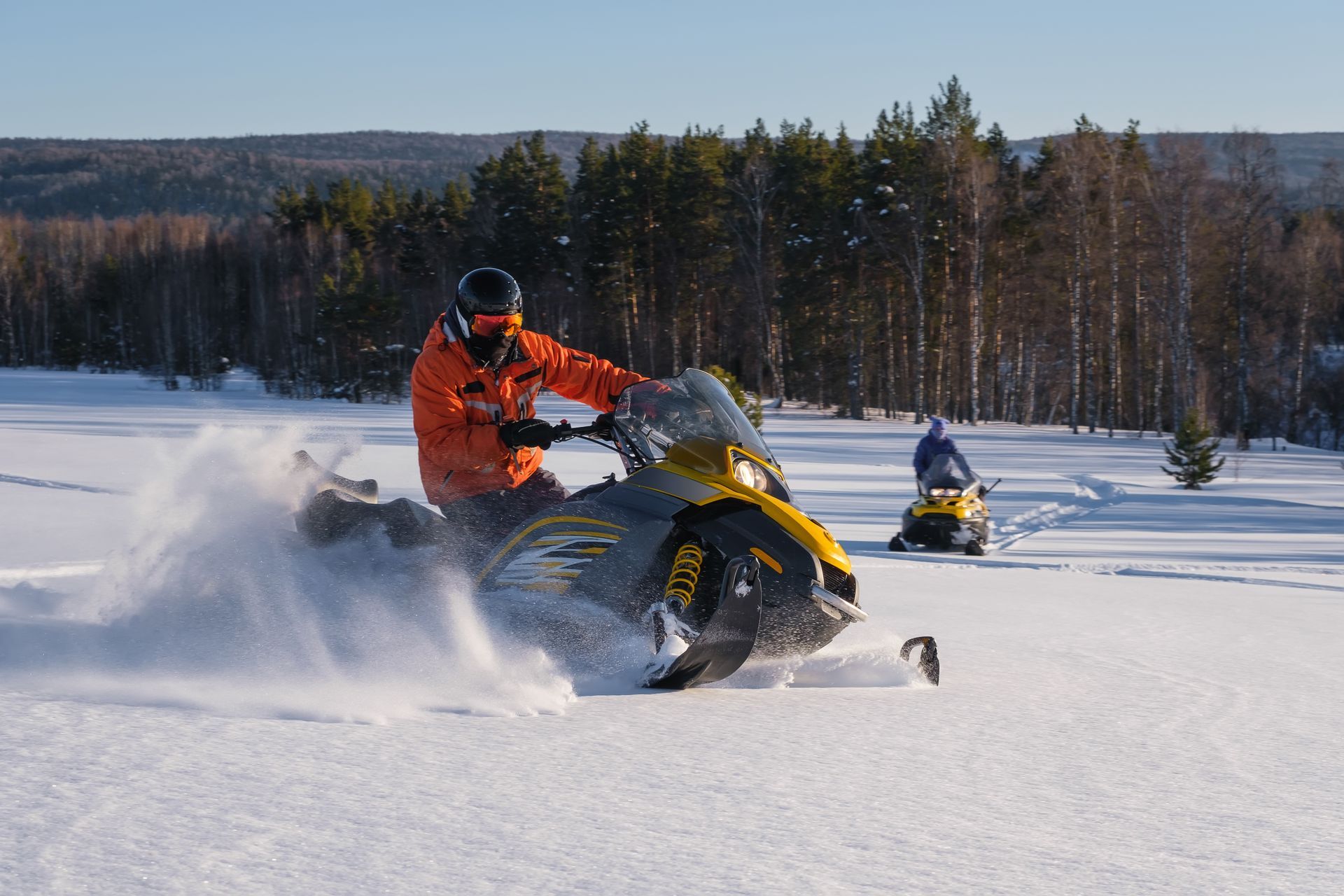 Snowmobile powersports vehicle riding in snow, showcasing reliability of custom wiring harnesses.