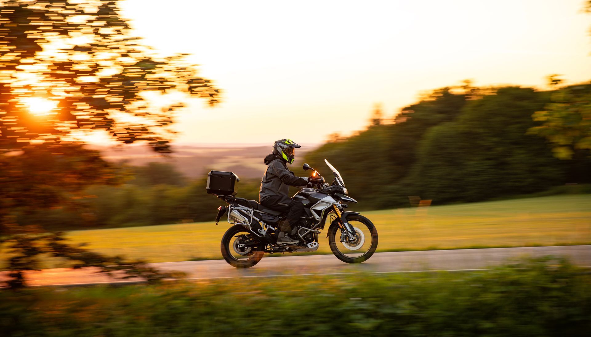 Motorcycle rider on country road at sunset, supported by custom wiring harnesses and cable assemblies.
