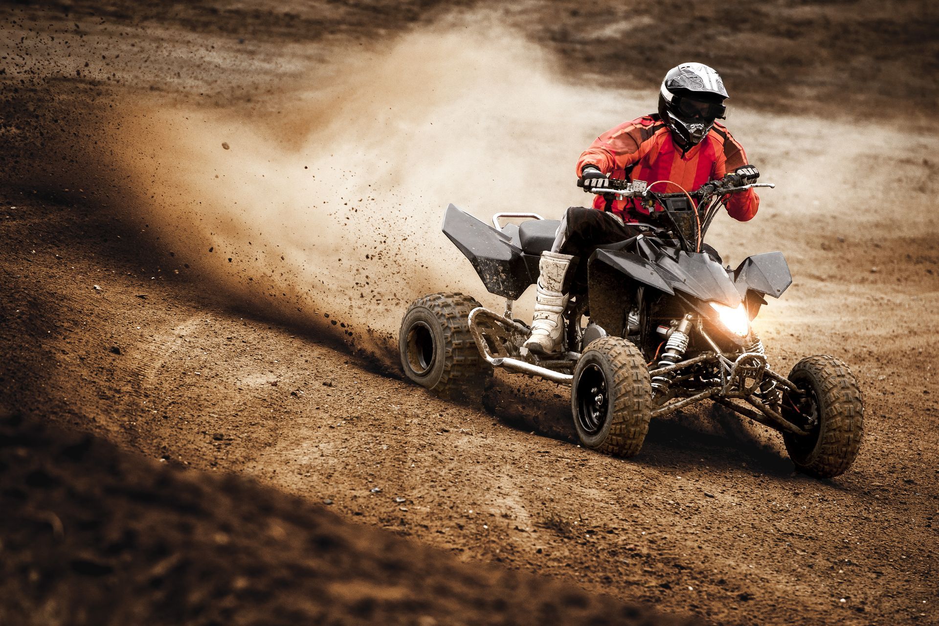 A man riding an ATV on a dirt track.