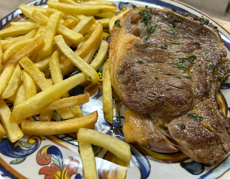 Bistecca alla griglia con patatine fritte servita su un piatto decorativo