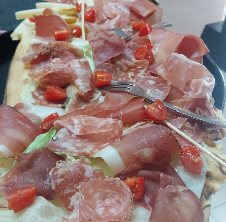 Fette di prosciutto e pomodorini su un vassoio da buffet con pinze da portata