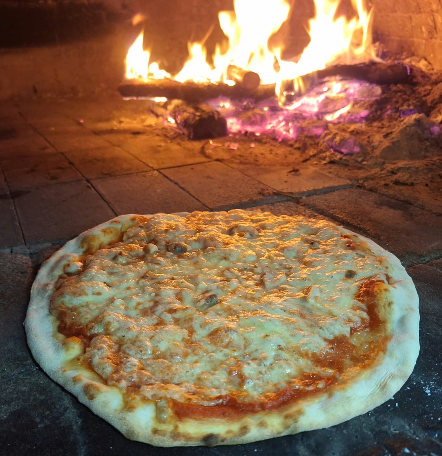 Pizza Margherita su un tagliere scuro con la scritta “Rabbio” ben visibile