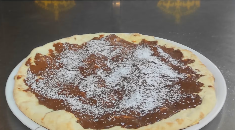 Piatto con un dessert abbondante ricoperto di cioccolato e spolverato di zucchero a velo