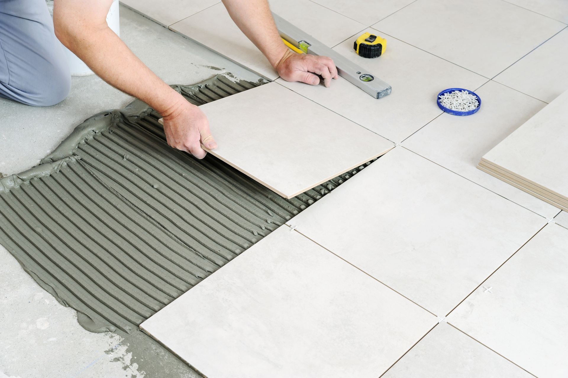 A person is laying tiles on a tiled floor.
