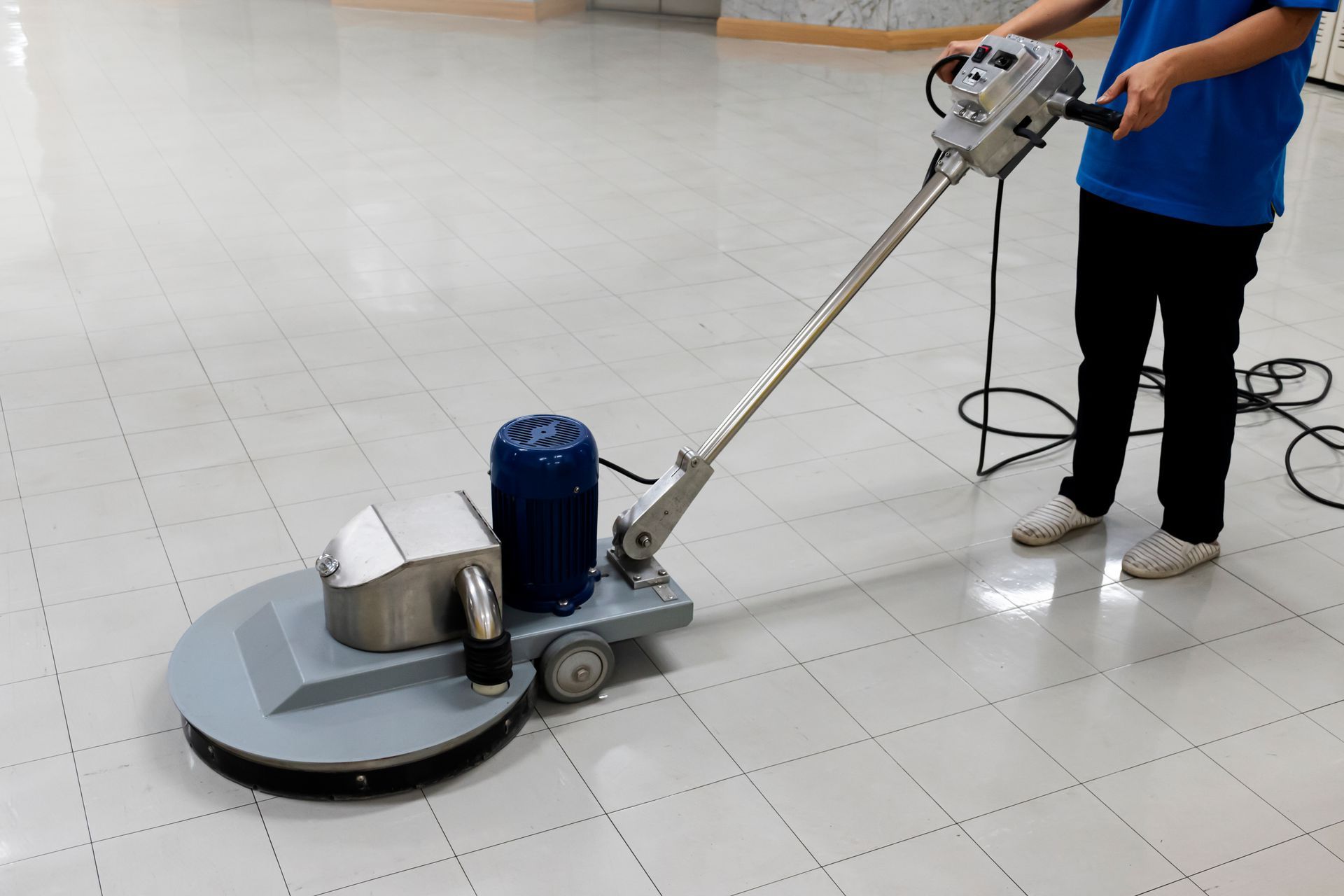 A person is using a machine to clean a tiled floor.