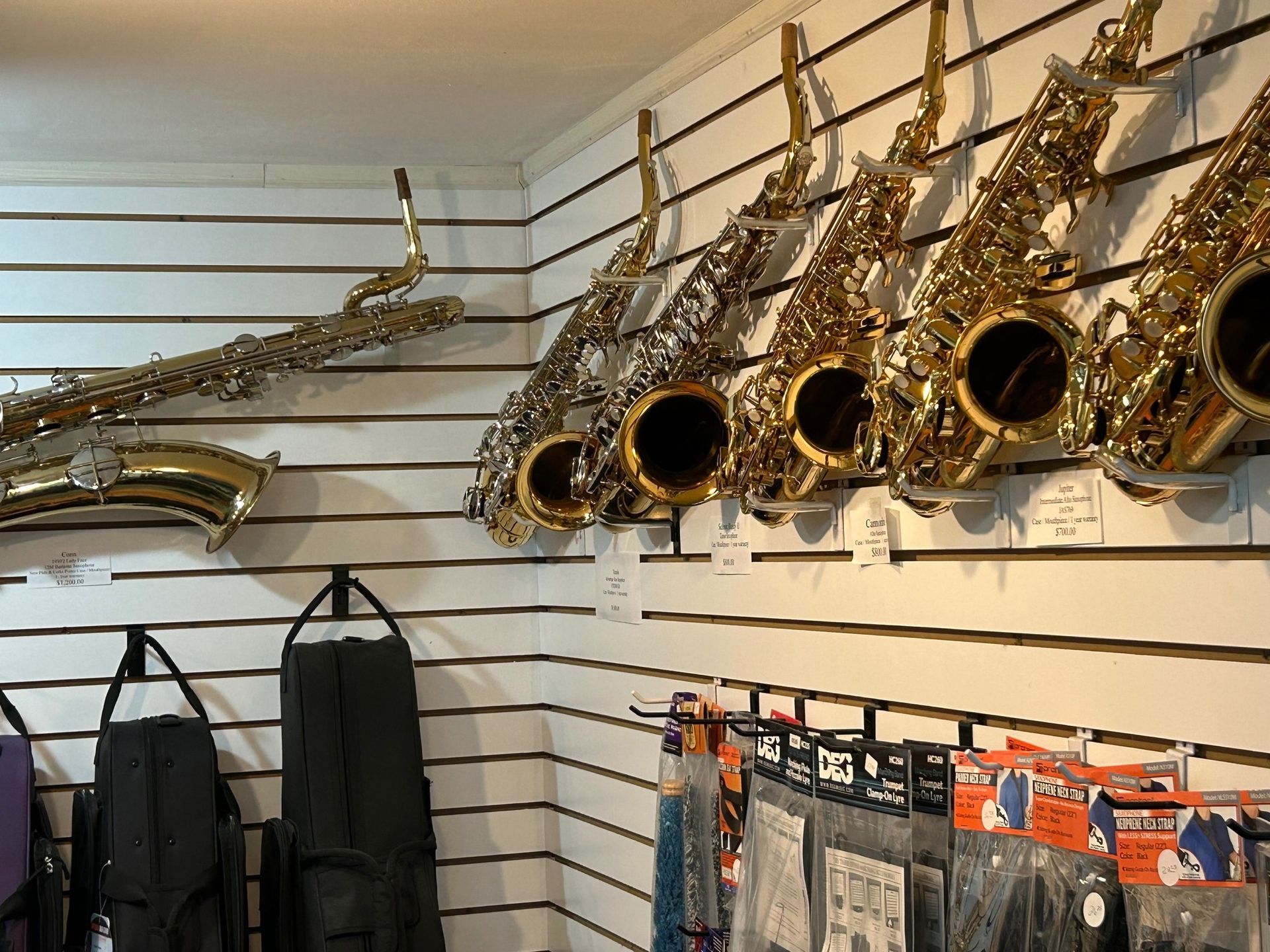 Saxophones on display in a music store, various finishes, with instrument cases and accessories.